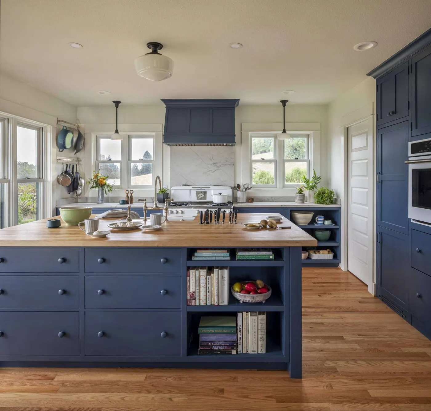 Kitchen in a farmhouse addition with navy island and open shelving